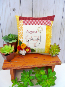 kitty cat holding the month of august hot balloon wool flowers